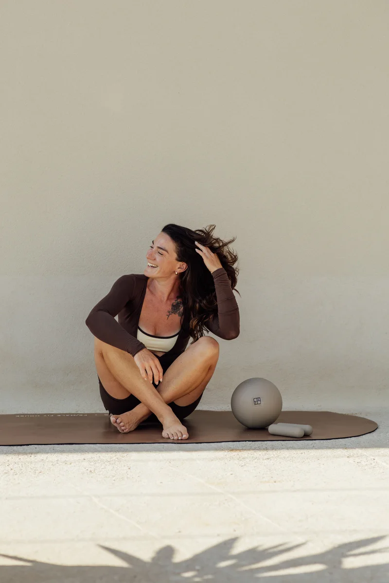 Professeure de Pilates en tenue marron sur son tapis
